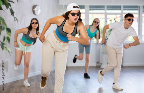 Positive emotional girl performing krump movements with group in modern dance studio. Form of artistic expression of young generation..