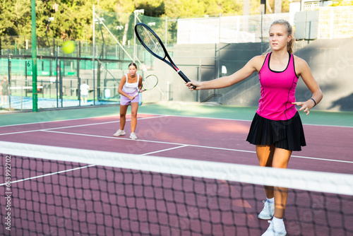 Caucasian woman wearing in pink t-shirt and skirt playing tennis match during training on court © JackF