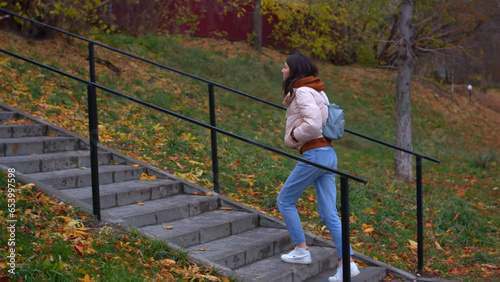 Young woman climbs stairs in park in autumn. Stock footage. Beautiful young woman walks in park in autumn. Woman climbs street stairs in park