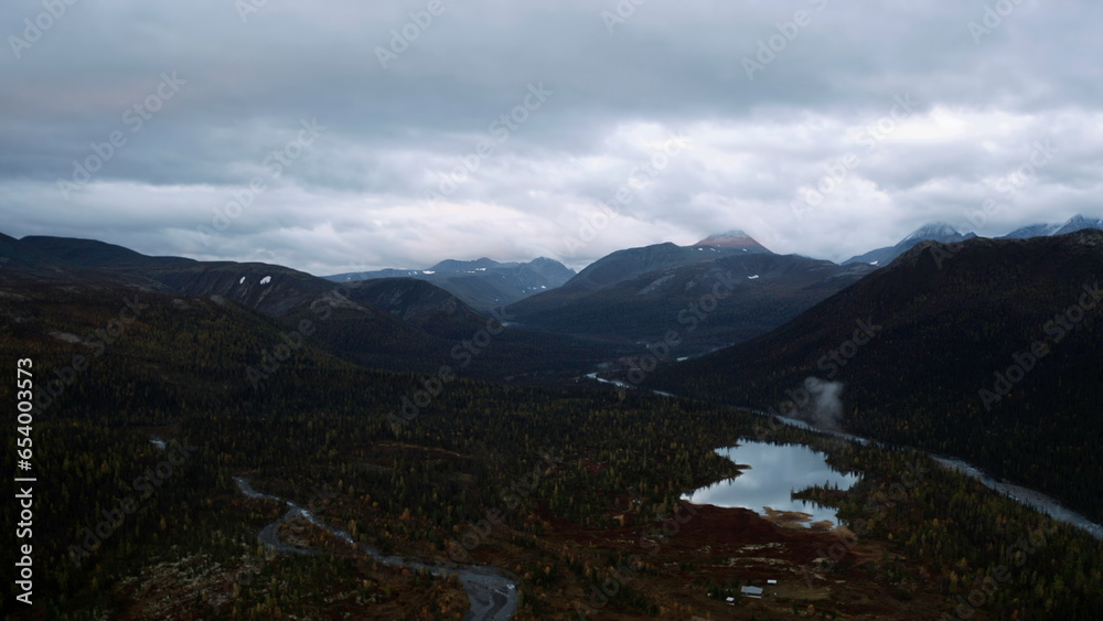 Obraz premium Aerial view of the natural reserve on an autumn day. Clip. Mountain range and heavy cloudy sky above forested valley.