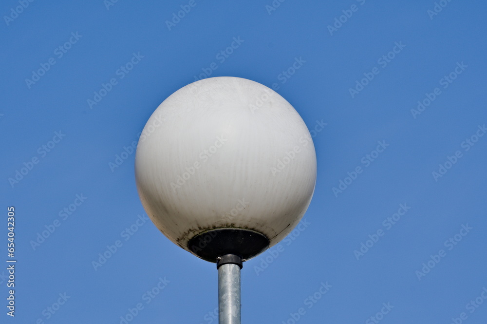 Round white streetlamp and blue sky background. Round white streetlamp and blue sky background.