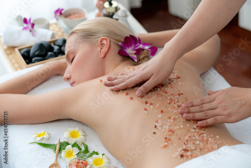 Woman customer having exfoliation treatment in luxury spa salon with warmth candle light ambient. Salt scrub beauty treatment in health spa body scrub. Quiescent © Summit Art Creations