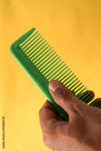 hand hold green comb on yellow background