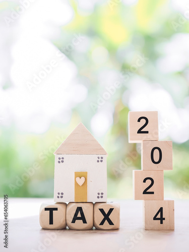 Wooden blocks with the word TAX 2024 and miniature house. The concept of Property investment, House mortgage, Real estste. photo