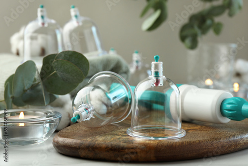 Plastic cups and hand pump on white table. Cupping therapy photo