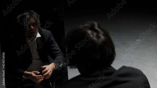 Desperate annoyed european man in rage and anger tearing his hair out. Stock footage. I made a terrible mistake, emotions in front of the mirror on a black background.