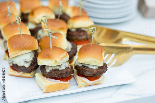 platter of mini cheeseburger sliders on plate with gold serving utensil 