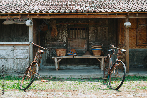 Traditional Javanese house is known as Joglo with two worn bicycles in front photo
