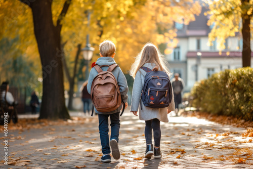 Boy and girl on the street going to school with a backpack on their backs, view from the rear
