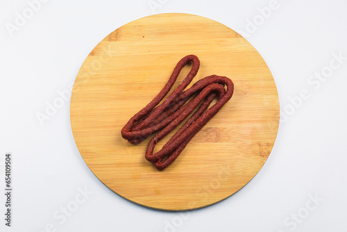 Delicious dried red meat sausages. Thin sausages on a wooden board on a white background.