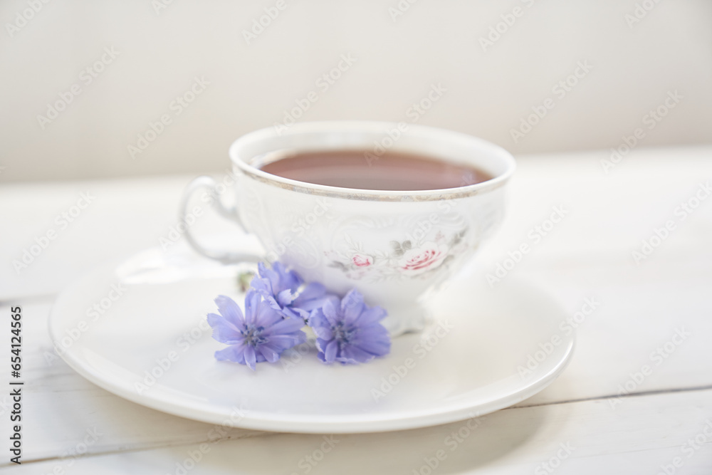 Against the background of a mug with an invigorating drink. Cichorium flowers in a saucer. Flowers of ordinary chicory or cichorium dioecious. With space to copy. High quality photo Against the background of a mug with an invigorating drink. Cichorium flowers in a saucer. Flowers of ordinary chicory or cichorium dioecious. With space to copy. High quality photo