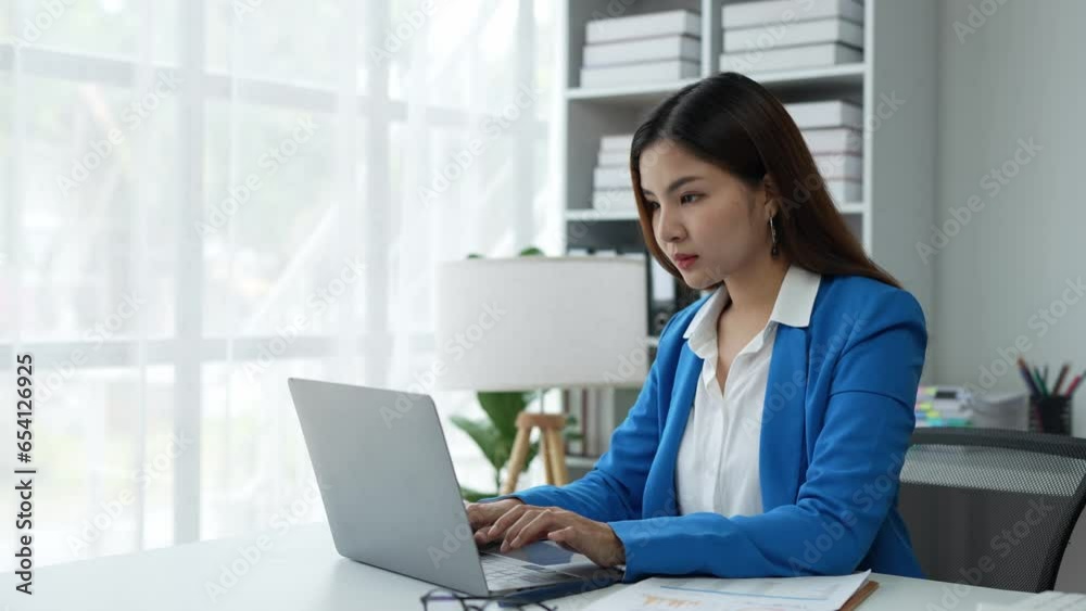 Asian businesswoman, self-employed working on a laptop computer typing e-commerce marketing financial report on real estate project in office management concept. Asian businesswoman, self-employed working on a laptop computer typing e-commerce marketing financial report on real estate project in office management concept.
