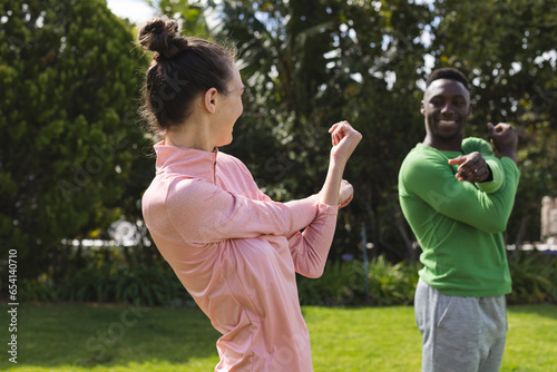 Happy diverse couple practicing yoga and stretching in garden