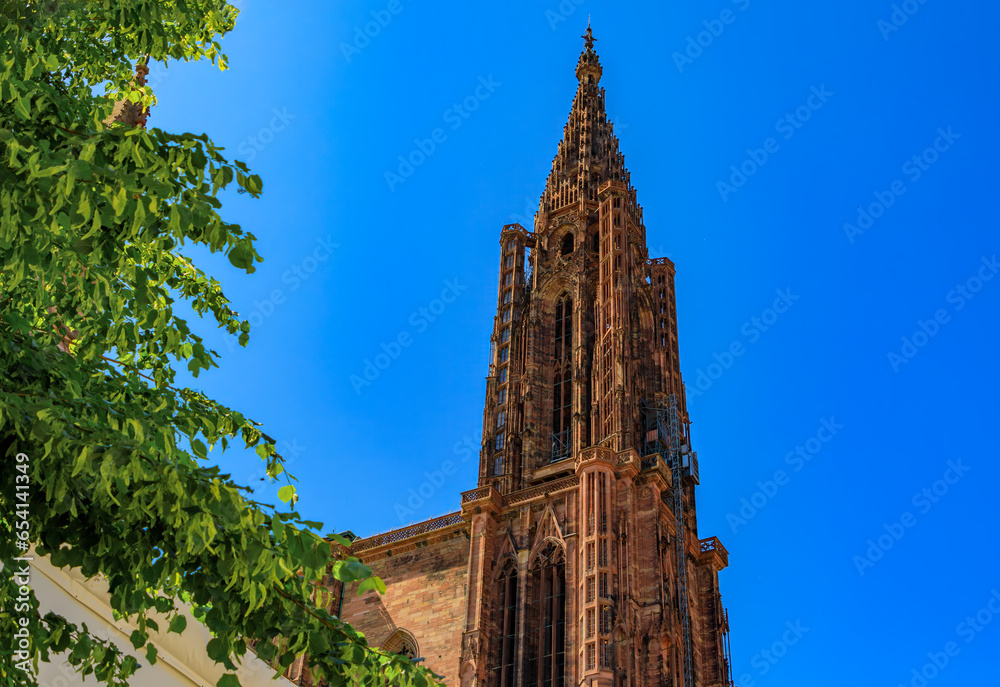 Facade and the spire of Notre Dame Cathedral and ornate traditional half timbered houses with steep roofs surrounding it in Strasbourg, Alsace, France Facade and the spire of Notre Dame Cathedral and ornate traditional half timbered houses with steep roofs surrounding it in Strasbourg, Alsace, France
