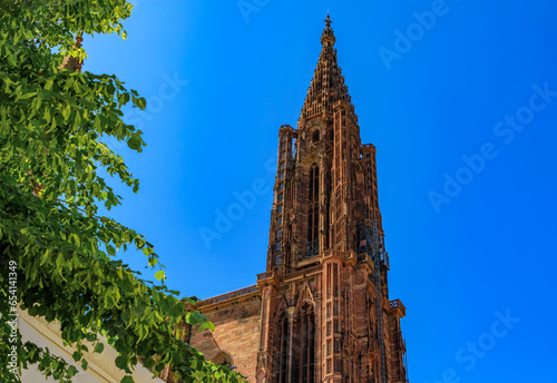 Facade and the spire of Notre Dame Cathedral and ornate traditional half timbered houses with steep roofs surrounding it in Strasbourg, Alsace, France