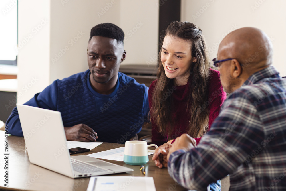 Diverse couple and biracial male financial advisor using laptop and discussing documents at home Diverse couple and biracial male financial advisor using laptop and discussing documents at home