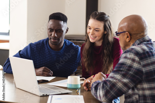 Diverse couple and biracial male financial advisor using laptop and discussing documents at home © WavebreakMediaMicro