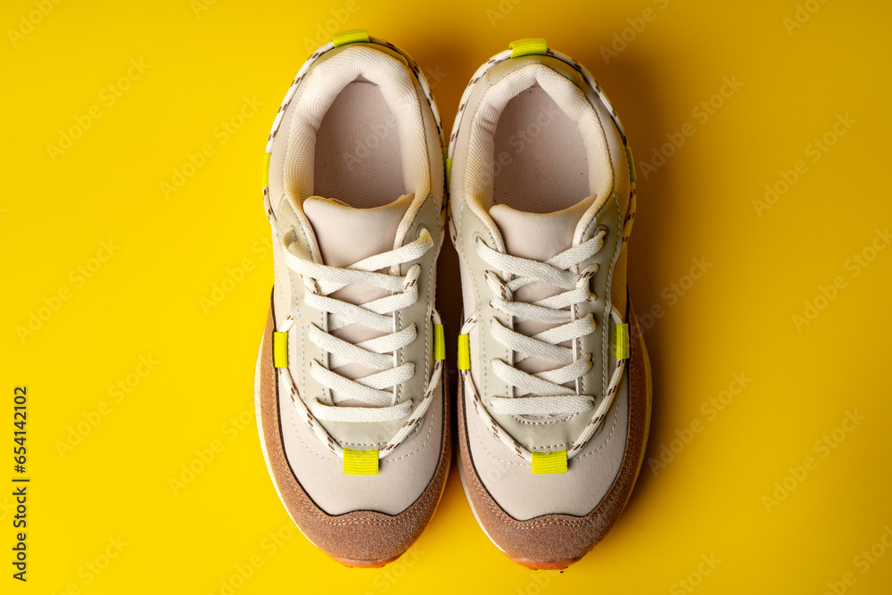 Beige sport running shoes on yellow studio background - obrazy, fototapety, plakaty 