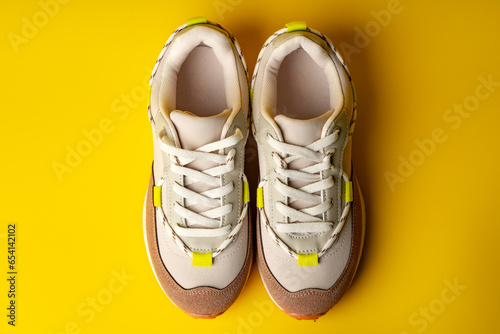 Beige sport running shoes on yellow studio background