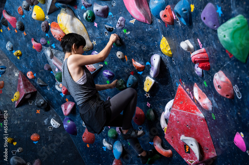 Young woman climbing the wall at a bouldering gym	 photo