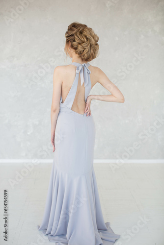 Full-length girl in lilac long dress with open back and evening hairstyle
