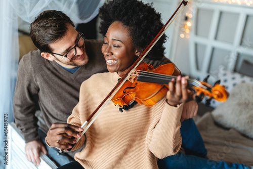 Young beautiful african american woman musician playing violin at home to her love