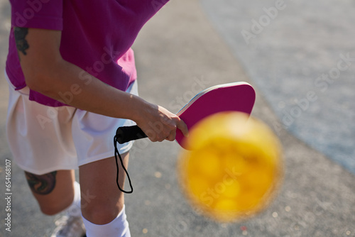 Pickler serving a ball with a racket. Pickleball player practicing outdoors
