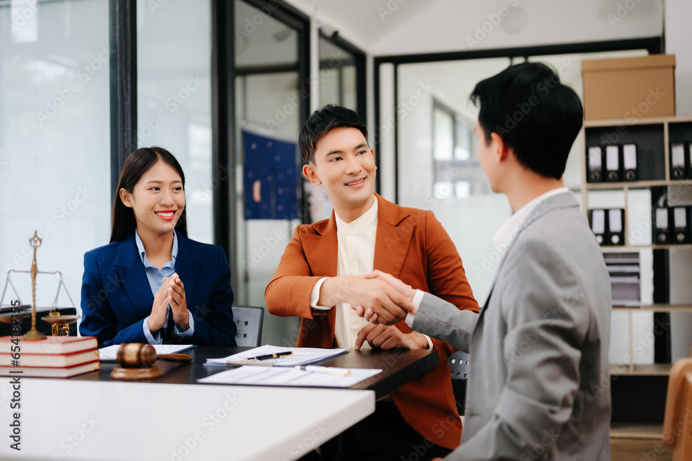 Man lawyer hand and women client shaking hand collaborate on working agreements with contract documents at the office.. Man lawyer hand and women client shaking hand collaborate on working agreements with contract documents at the office..