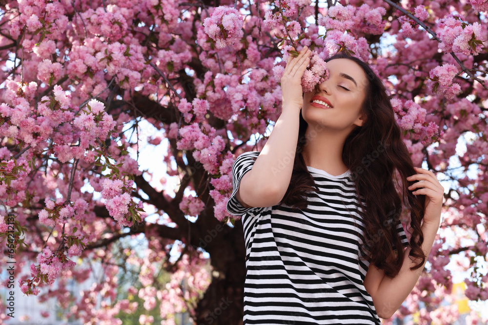 Beautiful woman near blossoming sakura tree on spring day Beautiful woman near blossoming sakura tree on spring day