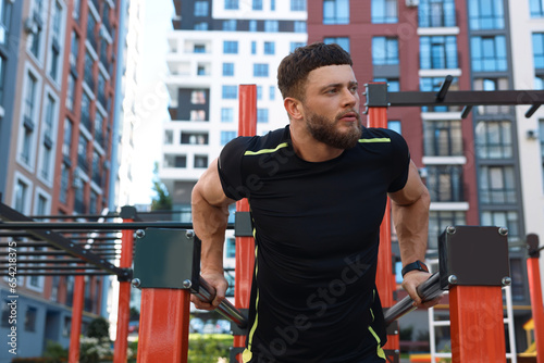 Man training on parallel bars at outdoor gym