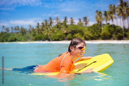 Canvas Print Child surfing on tropical beach. Surfer in ocean.