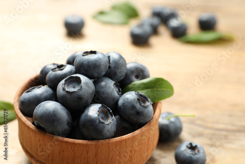 Bowl of tasty fresh blueberries on wooden table  closeup. Space for text
