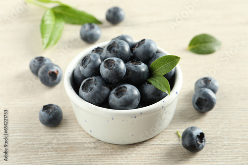 Bowl of fresh tasty blueberries on white wooden table, closeup