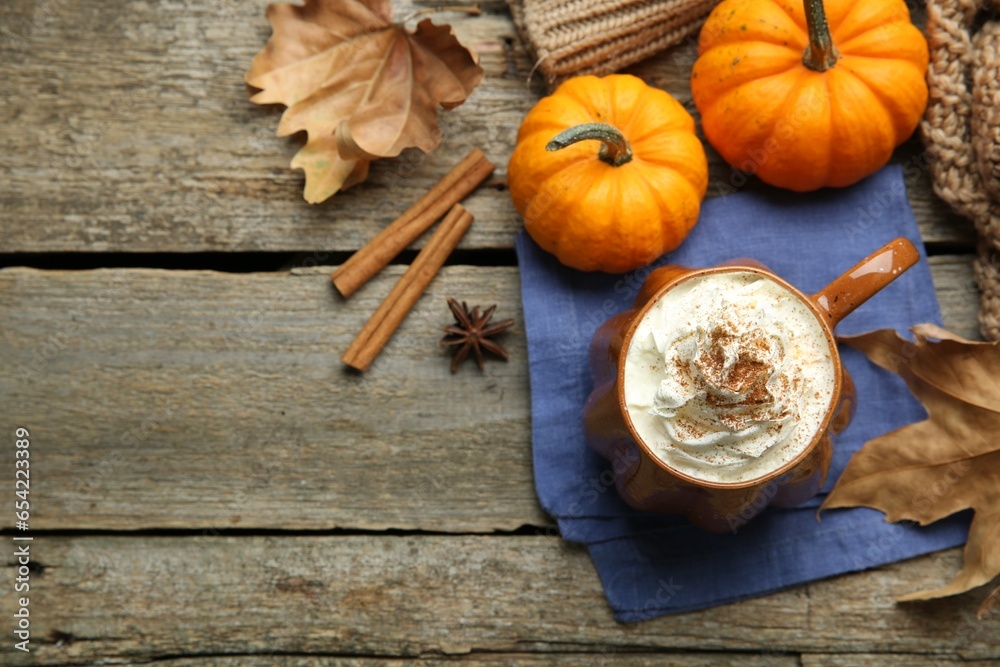 Mug of pumpkin spice latte with whipped cream, ingredients and dry leaves on wooden table, flat lay. Space for text Mug of pumpkin spice latte with whipped cream, ingredients and dry leaves on wooden table, flat lay. Space for text