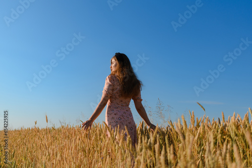 A woman in a beautiful dress in a rye field in the morning