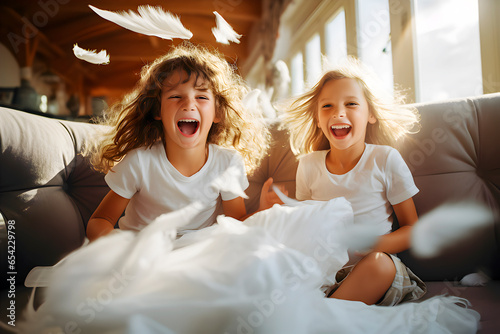 Dos niños entusiasmados felices y risueños se divierten en el interior de casa en una fiesta familiar con cogines en el sofá. photo