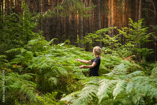 Forest baths, an adult woman in thickets of ferns restoring health and psyche in nature