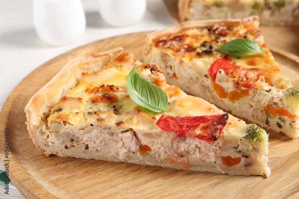 Tasty quiche with chicken, vegetables, basil and cheese on white table, closeup