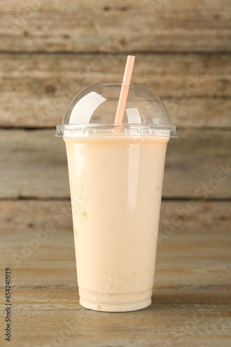 Plastic cup of tasty smoothie on wooden table