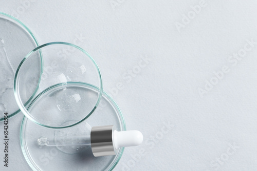 Petri dishes with samples of cosmetic oil and pipette on white background, flat lay. Space for text