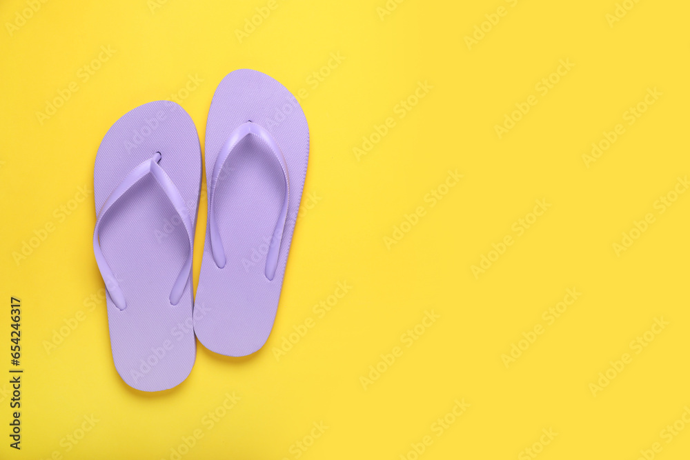 Stylish violet flip flops on yellow background, top view. Space for text Stylish violet flip flops on yellow background, top view. Space for text