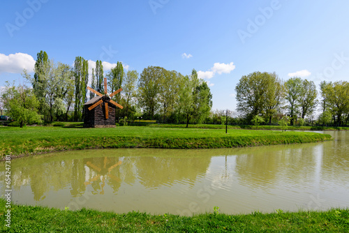 Small lake with a woodmill and an island from Chindiei Park (Parcul Chindiei) in Targoviste, Romania, in a sunny spring day with white clouds and blue sky photo