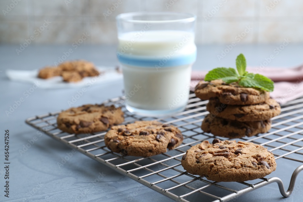 Fototapeta premium Tasty chocolate chip cookies, glass of milk and mint leaves on light grey table