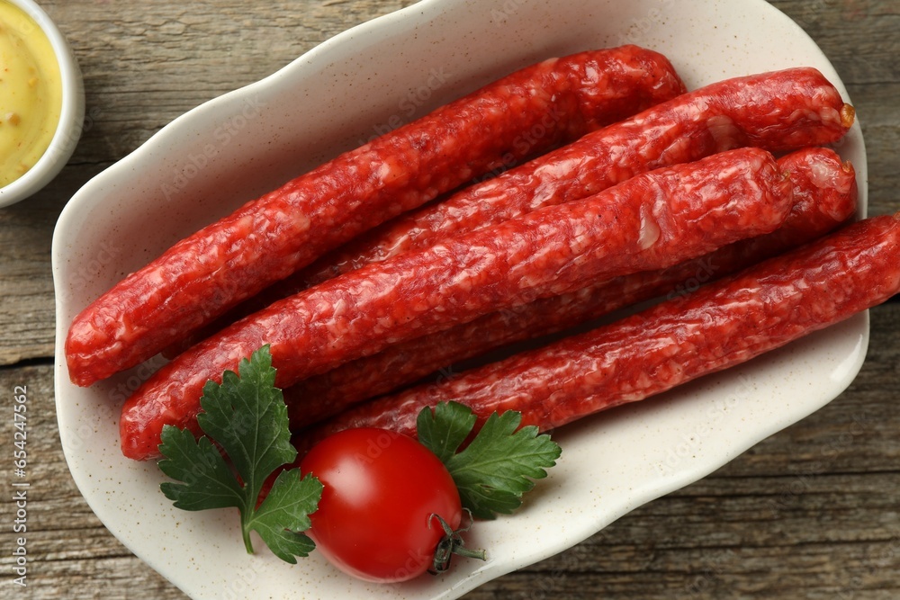 Bowl with thin dry smoked sausages, tomato and parsley on old wooden table, flat lay Bowl with thin dry smoked sausages, tomato and parsley on old wooden table, flat lay