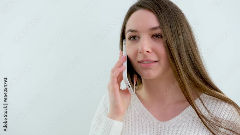 beautiful girl on cellular phone sad thoughtful girl with a phone in her hands on a white background long brown hair white sweater gentle smile embarrassment modesty. femininity beautiful girl on cellular phone sad thoughtful girl with a phone in her hands on a white background long brown hair white sweater gentle smile embarrassment modesty. femininity
