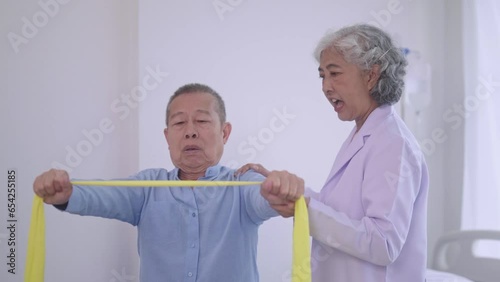 senior Asian women physical therapist caregiver assisting and exercising with mature asian man patient in a physic room with elastic resistance band rehabilitation treatment in a modern hospital. photo