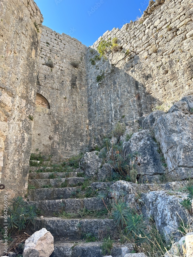 Ancient stones of the fortress wall. Ruins of an old fortress on top of a mountain. Historical fort on a mountain by the sea. Croatia, Ugljan island, September 7, 2023