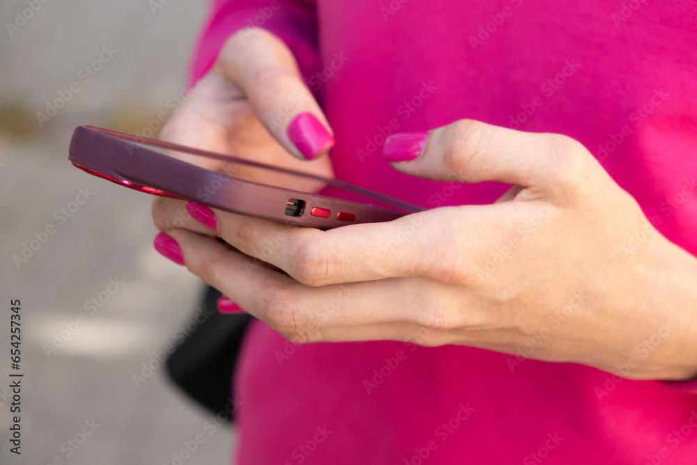 Woman uses smartphone, mobile phone, outdoors, close-up hands