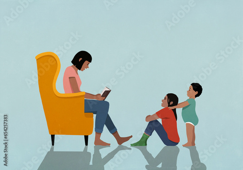 Mother in armchair reading book to daughter and son at home
 photo