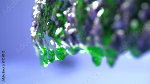 Drops of green epoxy resin flow profusely from the dark base. blue background, close-up, 4K. photo